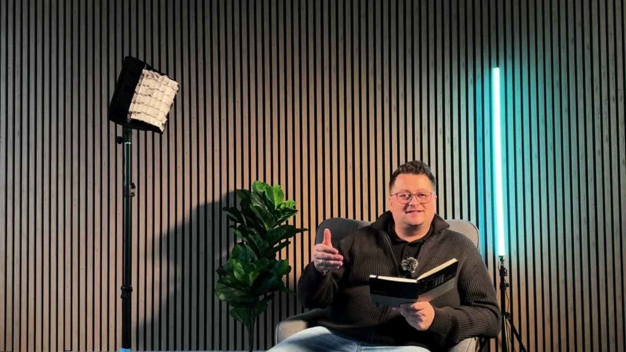 Speciālists studijā ar piezīmju grāmatu rokās stāsta par akumulatora izvēli